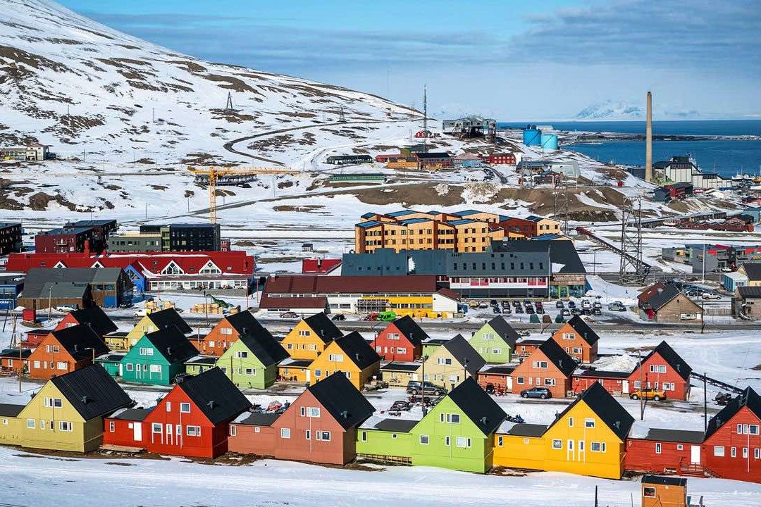 Een levendig stadje bedekt met sneeuw, met kleurrijke gebouwen tegen een winterlandschap.